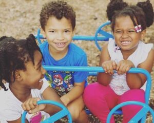 three preschool age children playing outside 						